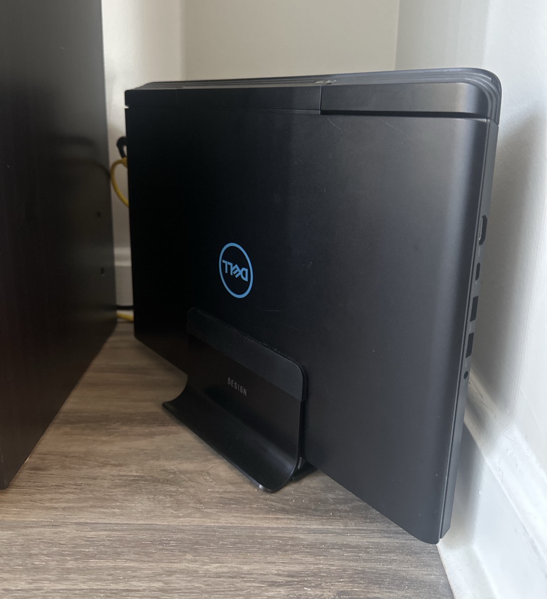 The Dell laptop standing upright in a stand in the corner of the room, lid shut
